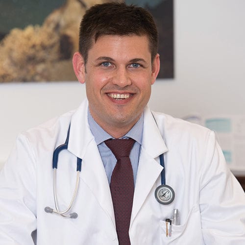 Portrait von Dr. Stefan Wöhrer im weissen Arztkittel und Stetoskop um den Hals.